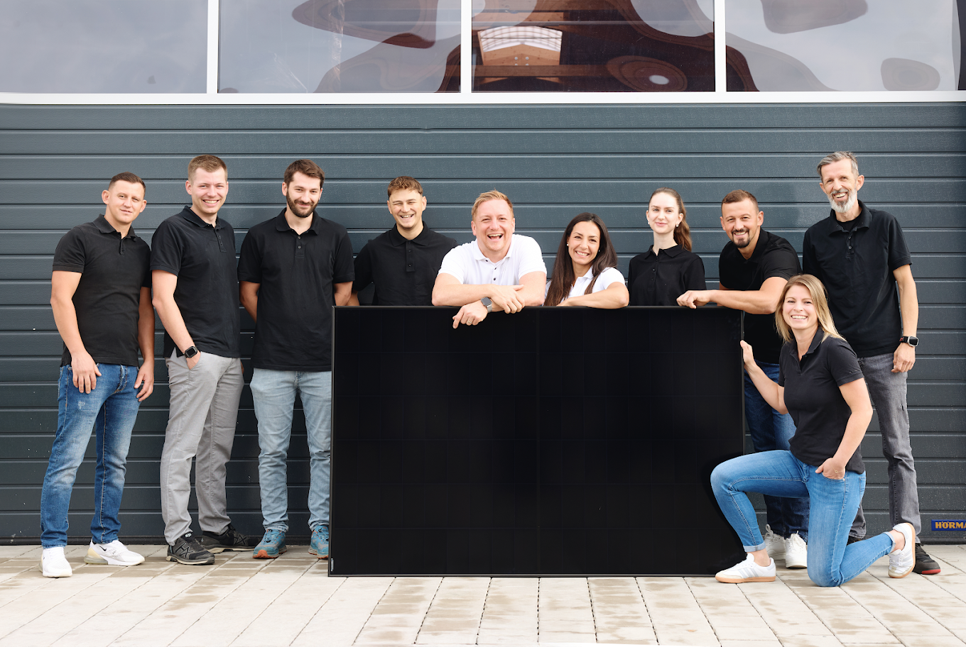 Das Team von Hirschberger Energietechnik mit Photovoltaikmodul und dunkler Wärmepumpe
