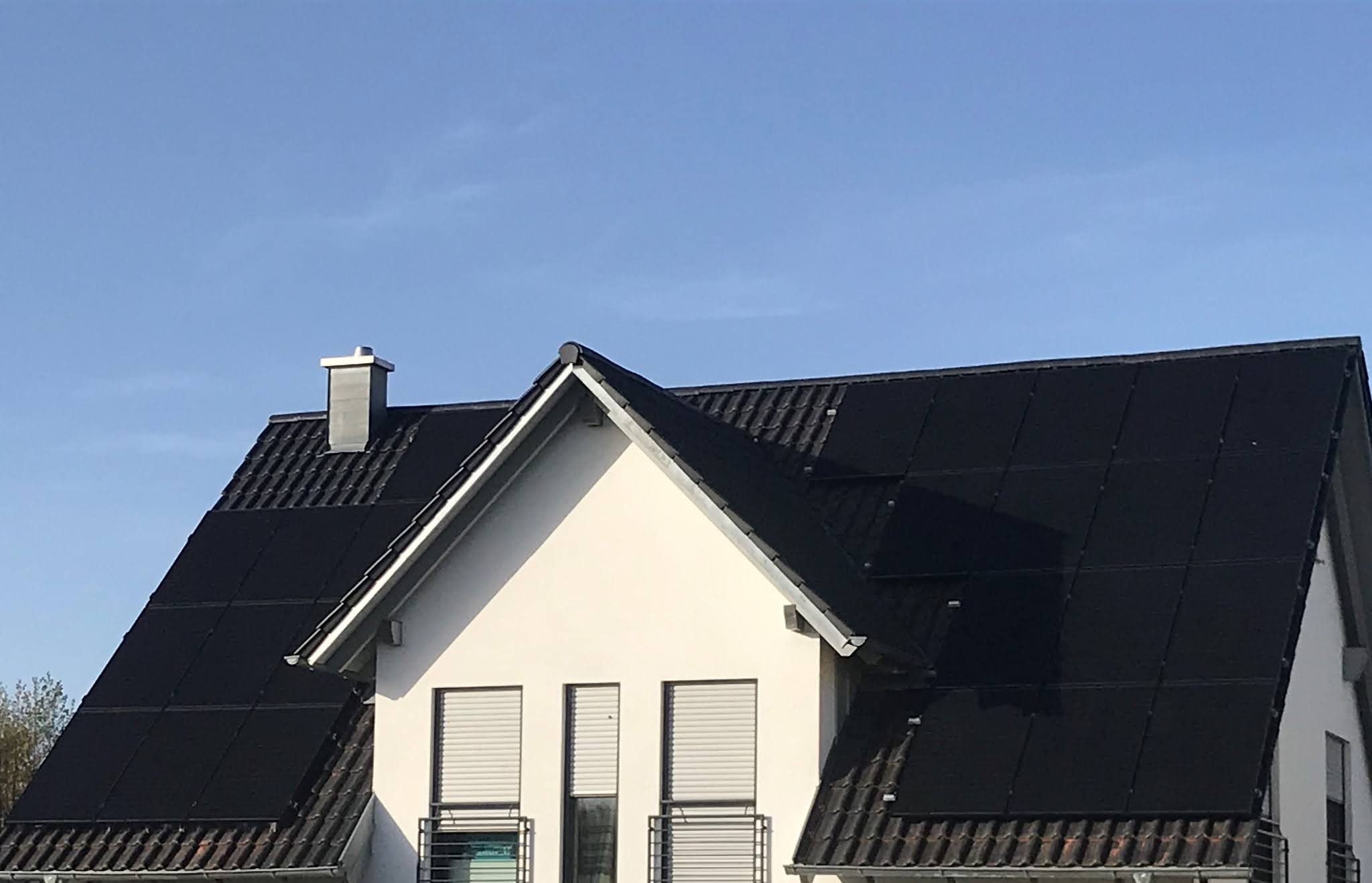 Schwarze Solarmodule auf dem dunklen Dach eines hellen Wohnhauses mit Dachgaube – Foto aus der Rezension von Thomas Stanka